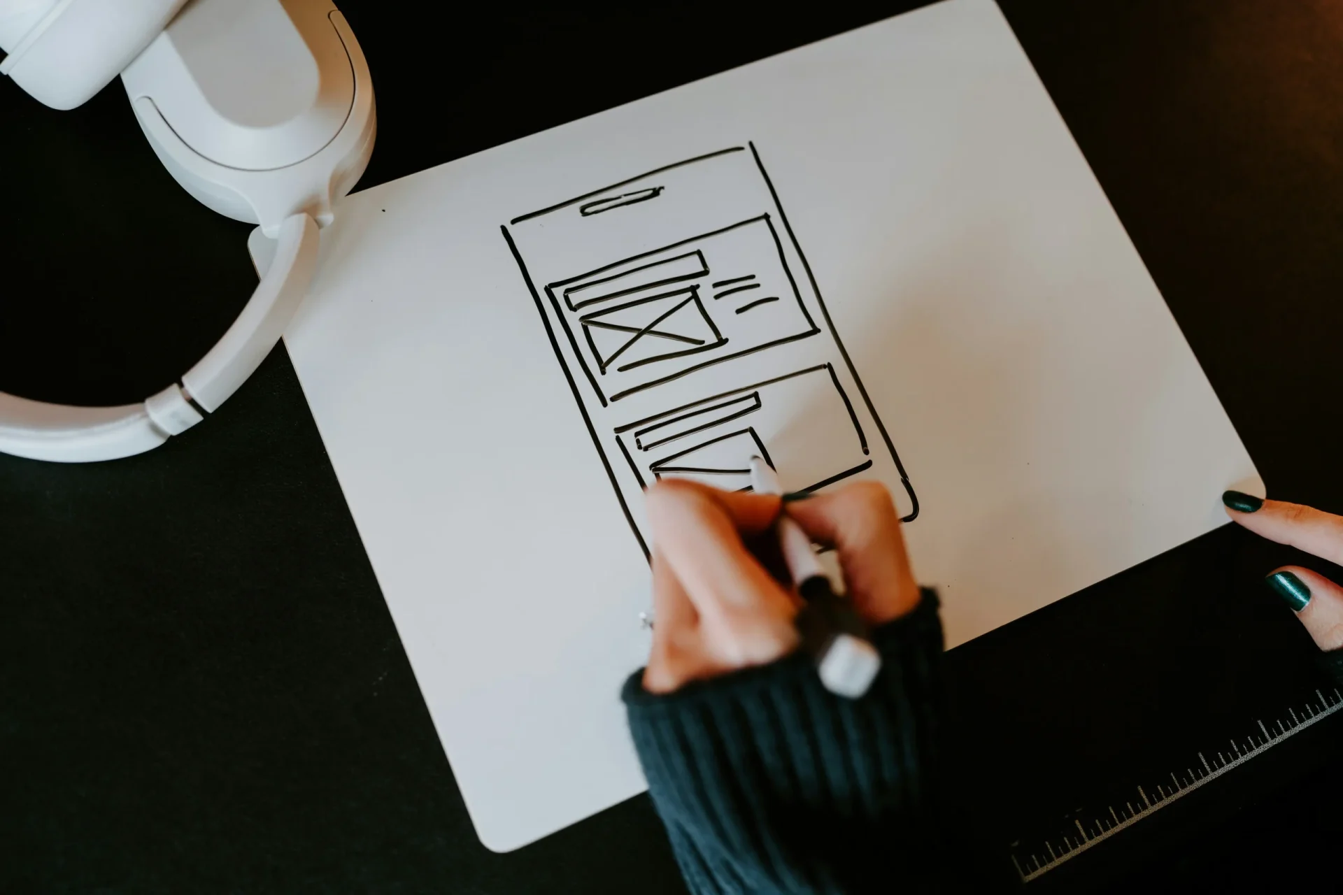 Designer sketching website wireframe layout on paper with pen and design tools